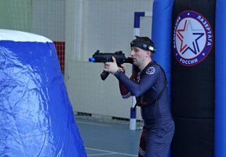 Игрок LASERWAR с автоматом за синим укрытием.